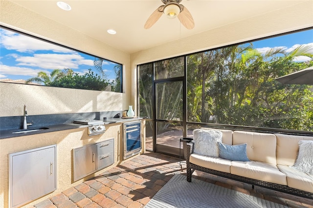 sunroom / solarium featuring ceiling fan, sink, and wine cooler