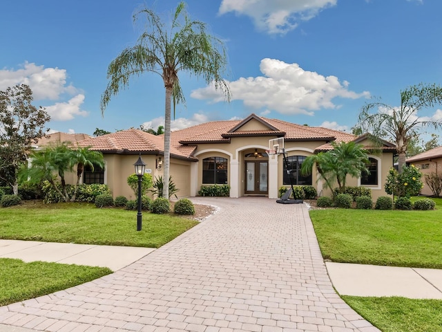 mediterranean / spanish home featuring a front lawn and french doors