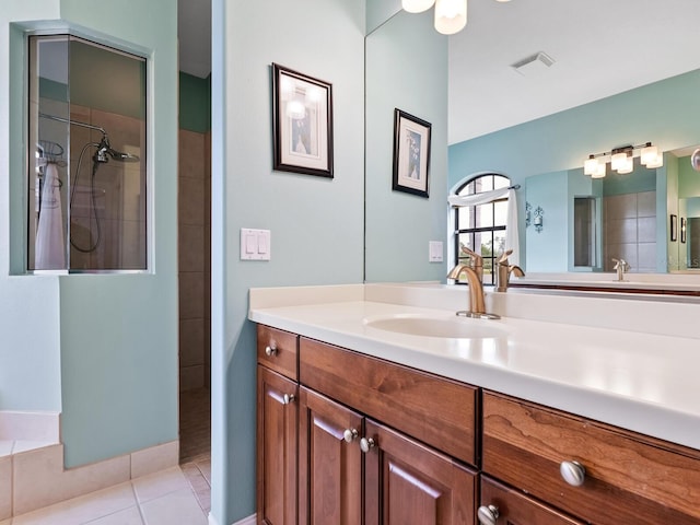 bathroom with tile patterned flooring, vanity, and tiled shower