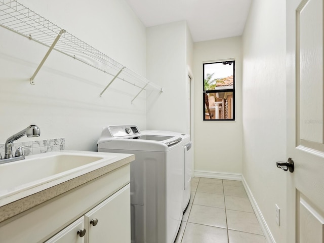 laundry room with cabinets, light tile patterned floors, washer and clothes dryer, and sink