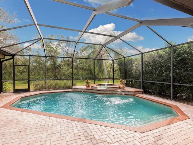 view of pool featuring glass enclosure, an in ground hot tub, and a patio area