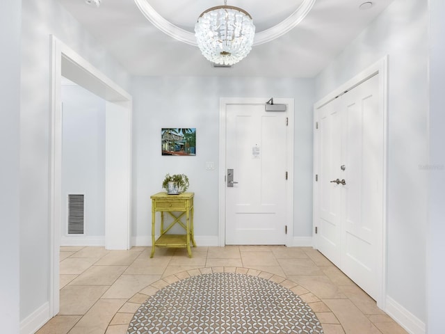 tiled foyer entrance featuring a chandelier and a tray ceiling