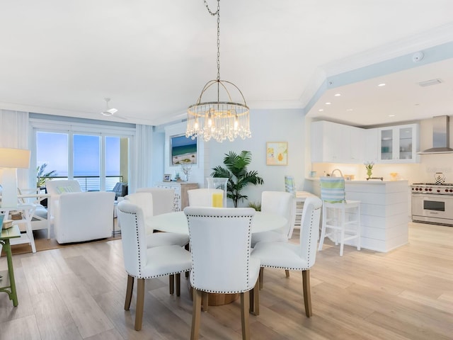 dining area with crown molding, an inviting chandelier, and light hardwood / wood-style flooring