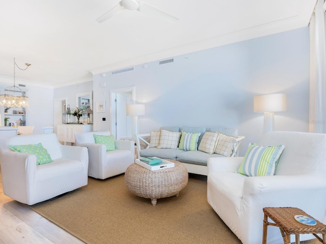 living room featuring ceiling fan with notable chandelier, wood-type flooring, and ornamental molding