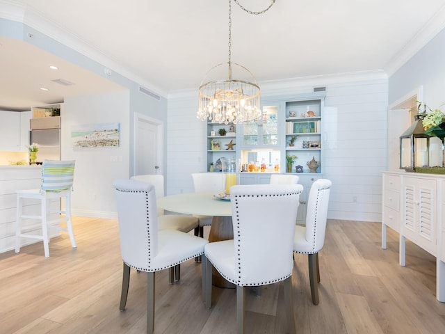 dining area with light wood-type flooring, crown molding, and an inviting chandelier