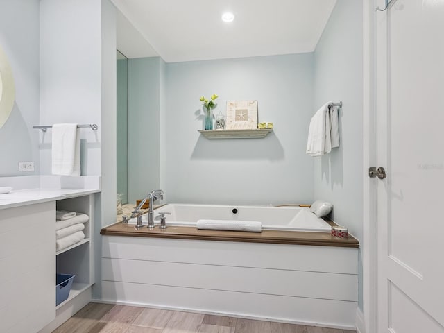 bathroom with hardwood / wood-style floors and a tub to relax in