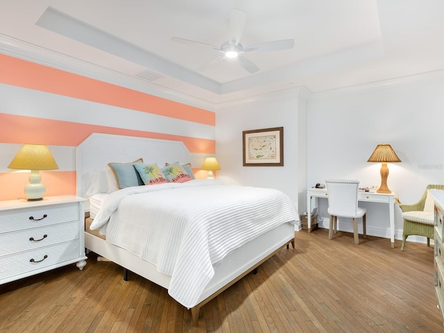 bedroom with ceiling fan, a raised ceiling, and wood-type flooring