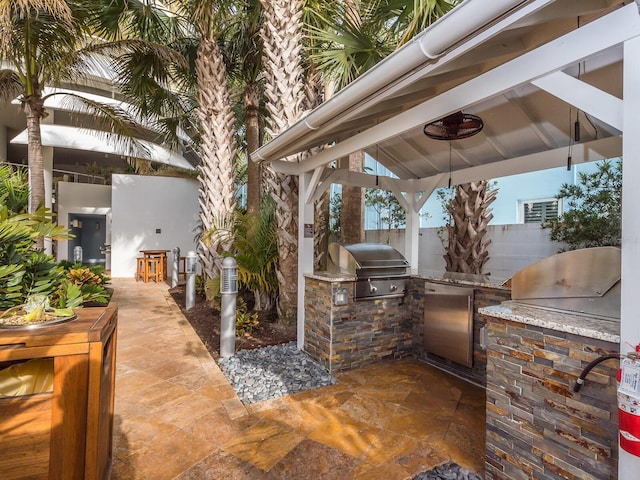 view of patio featuring area for grilling, exterior bar, an outdoor kitchen, and a gazebo