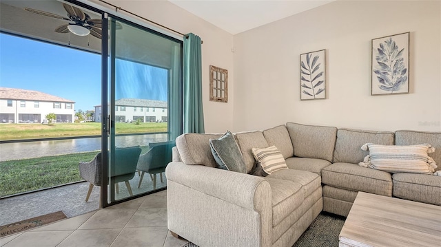 living room with ceiling fan, a water view, and light tile patterned floors