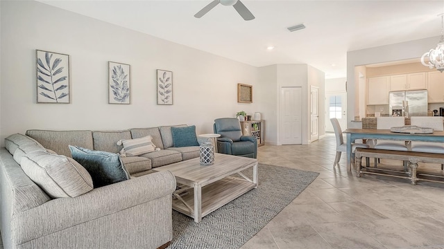 living room with ceiling fan with notable chandelier and light tile patterned floors