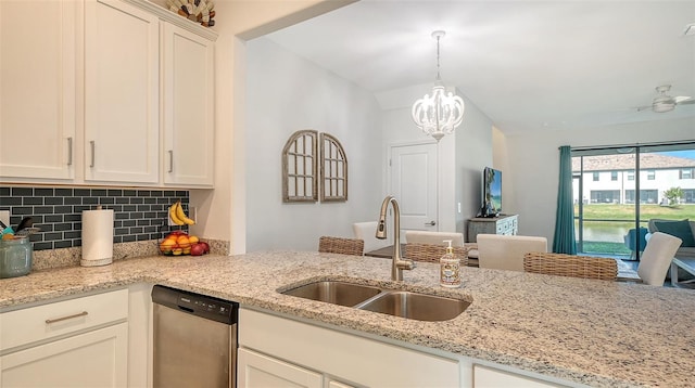 kitchen with light stone countertops, sink, an inviting chandelier, stainless steel dishwasher, and backsplash