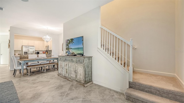 stairway with tile patterned floors and an inviting chandelier