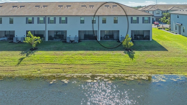 back of house with cooling unit, a yard, and a water view