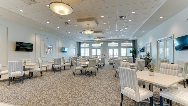 dining space featuring carpet flooring, a high ceiling, and a paneled ceiling