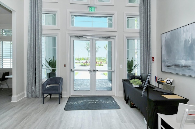 doorway featuring a towering ceiling, french doors, and light wood-type flooring