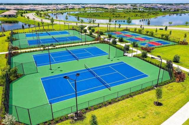 view of tennis court featuring a yard and a water view