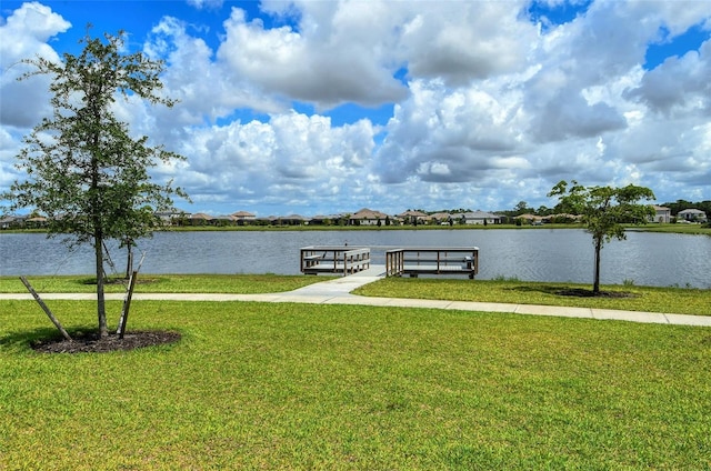 view of dock with a yard and a water view