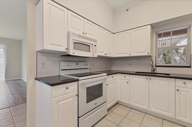 kitchen with light tile patterned flooring, white appliances, white cabinetry, and sink