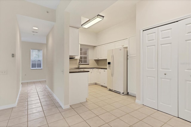 kitchen with decorative backsplash, white appliances, sink, light tile patterned floors, and white cabinetry