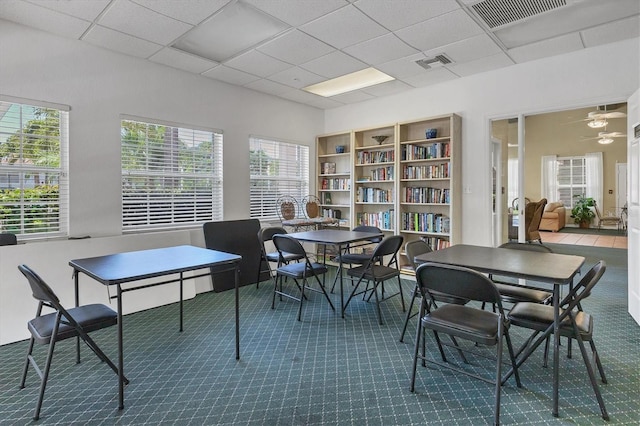 dining space with carpet flooring, a wealth of natural light, and a drop ceiling