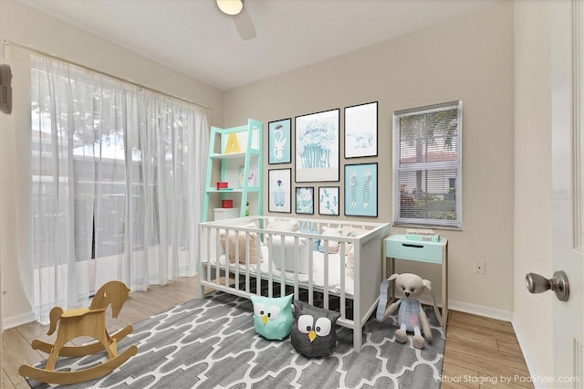 bedroom featuring ceiling fan, a crib, and light wood-type flooring