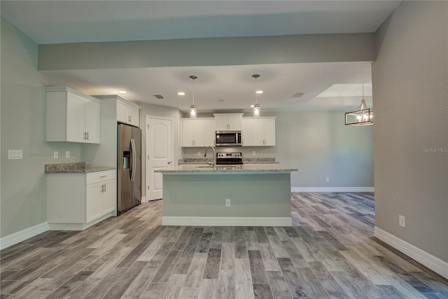 kitchen featuring appliances with stainless steel finishes, decorative light fixtures, and light hardwood / wood-style floors