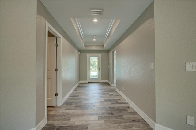 entryway with a tray ceiling, light hardwood / wood-style flooring, and ornamental molding