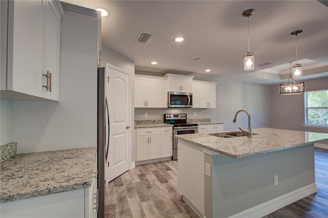 kitchen with sink, appliances with stainless steel finishes, decorative light fixtures, white cabinets, and light wood-type flooring