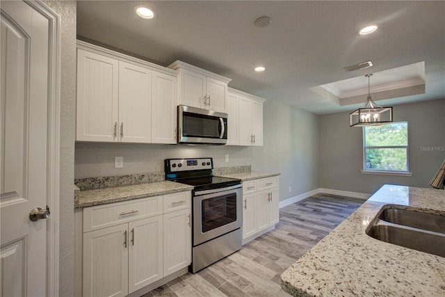 kitchen with ornamental molding, light hardwood / wood-style floors, light stone counters, white cabinetry, and stainless steel appliances