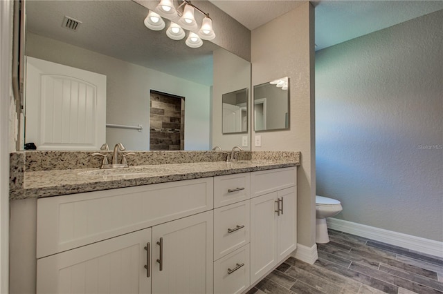 bathroom with hardwood / wood-style floors, vanity, toilet, and a textured ceiling