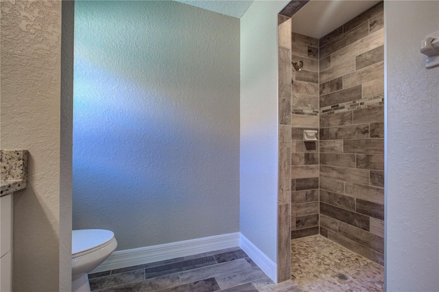 bathroom with tiled shower and toilet