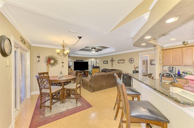 dining room featuring a textured ceiling, light wood-type flooring, ceiling fan with notable chandelier, and ornamental molding