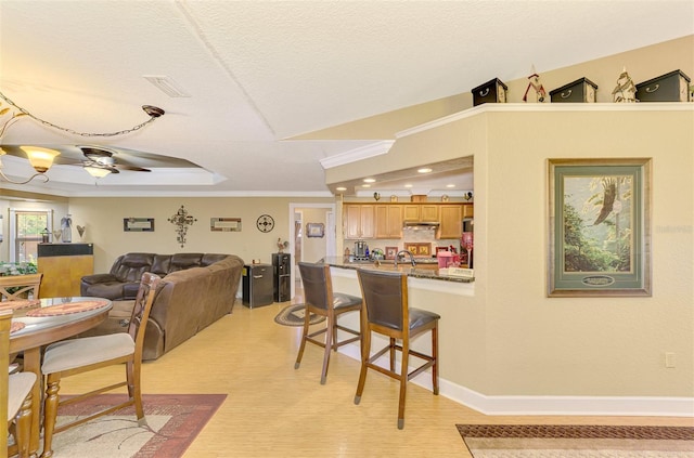 dining area with a textured ceiling, ceiling fan, ornamental molding, and sink