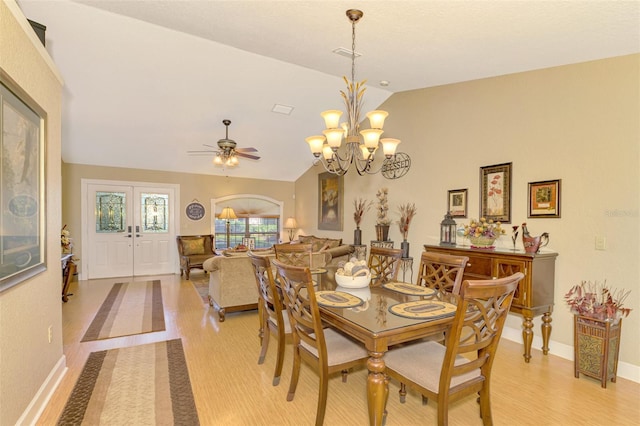 dining room with ceiling fan with notable chandelier, french doors, light wood-type flooring, and lofted ceiling