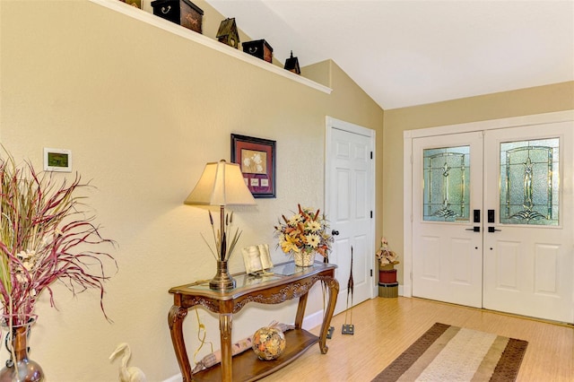 foyer entrance featuring french doors, lofted ceiling, and hardwood / wood-style flooring