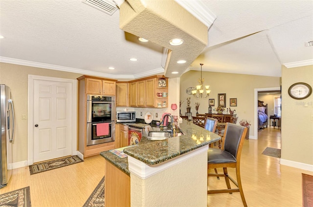 kitchen with kitchen peninsula, appliances with stainless steel finishes, a textured ceiling, and sink