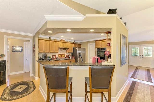 kitchen with stainless steel appliances, crown molding, dark stone counters, a textured ceiling, and a breakfast bar