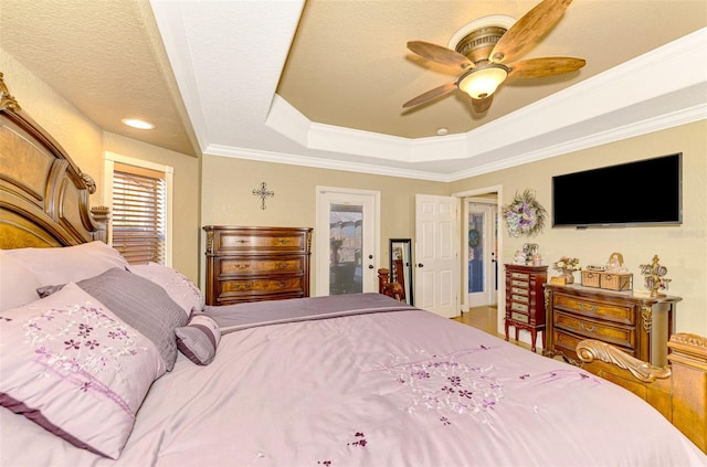 bedroom featuring a raised ceiling, ceiling fan, a textured ceiling, and ornamental molding