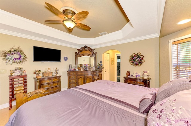 bedroom with ornamental molding, a textured ceiling, a raised ceiling, ceiling fan, and hardwood / wood-style floors