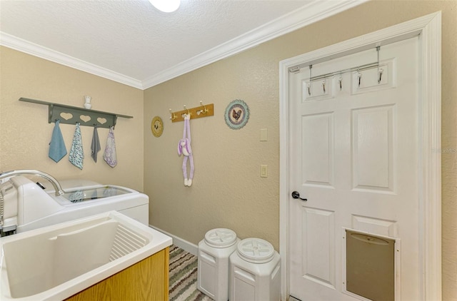 washroom with a textured ceiling, washer and clothes dryer, ornamental molding, and sink