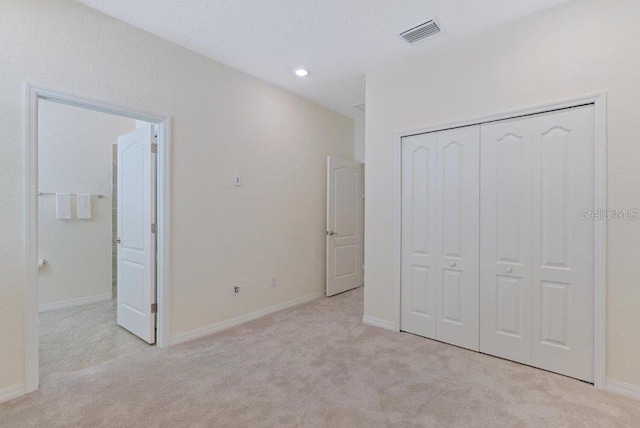 unfurnished bedroom featuring light carpet and a closet