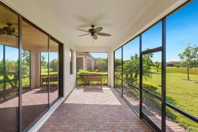 unfurnished sunroom featuring ceiling fan and a wealth of natural light