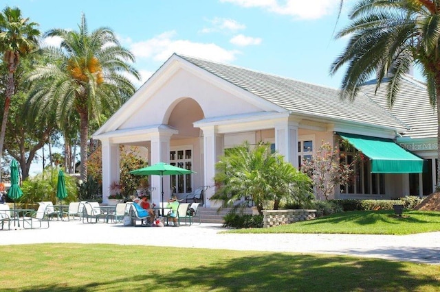 rear view of house featuring a lawn and a patio