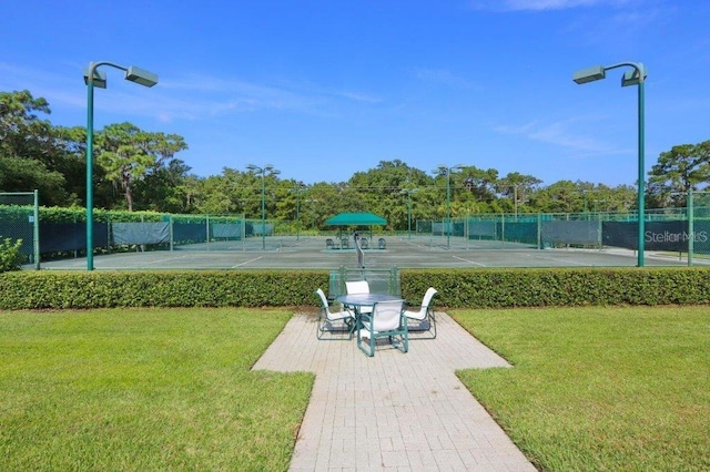 view of home's community with tennis court and a lawn