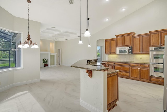 kitchen with pendant lighting, appliances with stainless steel finishes, a kitchen bar, decorative backsplash, and sink