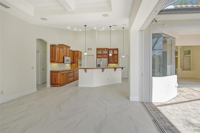 kitchen with appliances with stainless steel finishes, decorative light fixtures, crown molding, a breakfast bar, and a center island