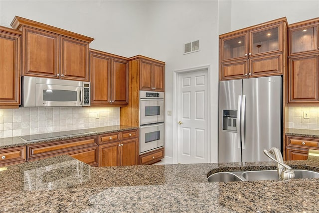 kitchen featuring tasteful backsplash, sink, stone counters, and stainless steel appliances