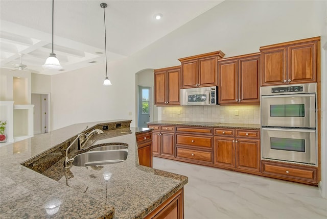 kitchen with light stone countertops, sink, hanging light fixtures, and stainless steel appliances