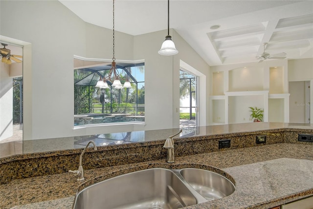 kitchen with coffered ceiling, beam ceiling, hanging light fixtures, ceiling fan with notable chandelier, and sink