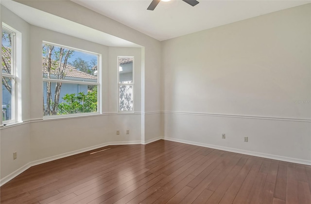 empty room with ceiling fan, dark hardwood / wood-style flooring, and a healthy amount of sunlight